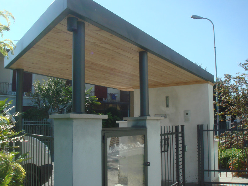 Copertura moderna in legno e metallo sopra l'ingresso di un cancello pedonale