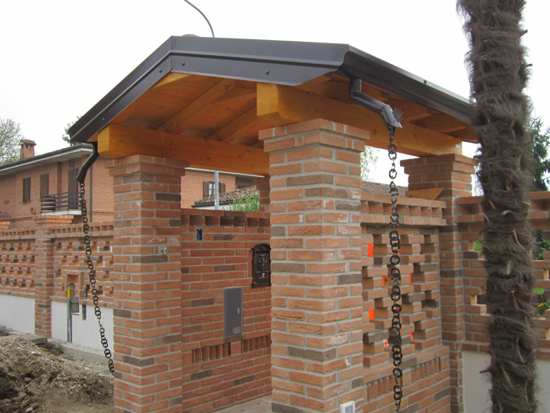 Tettoia in legno con pilastri in mattoni per la copertura dell'ingresso esterno