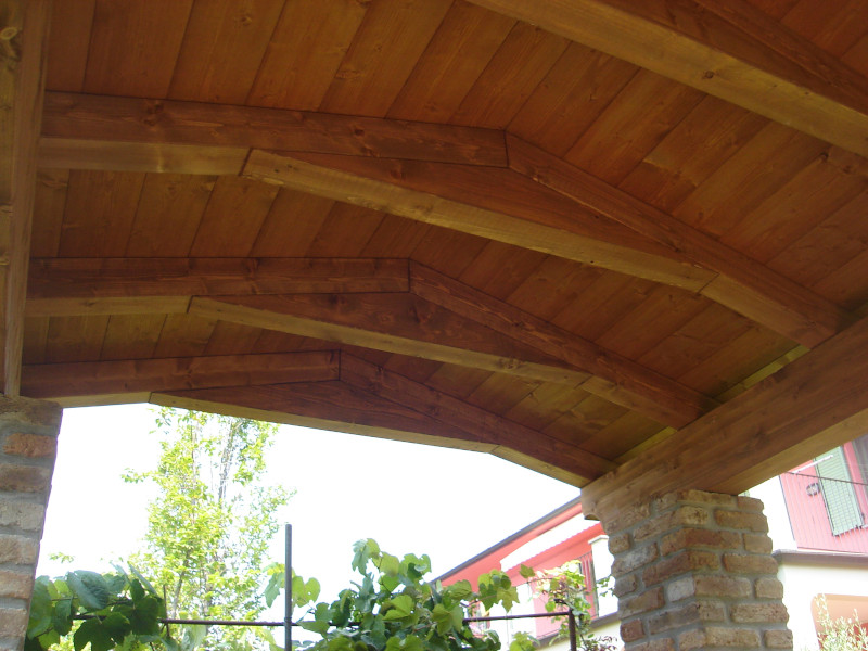 Intradosso di una copertura in legno con travi a vista e pilastri in muratura.