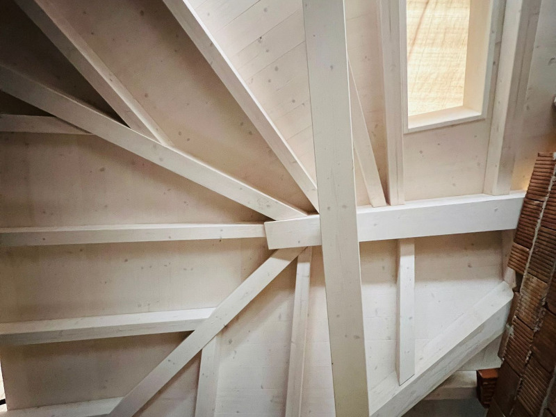 Interno con struttura di tetto in legno a travi a vista e lucernario